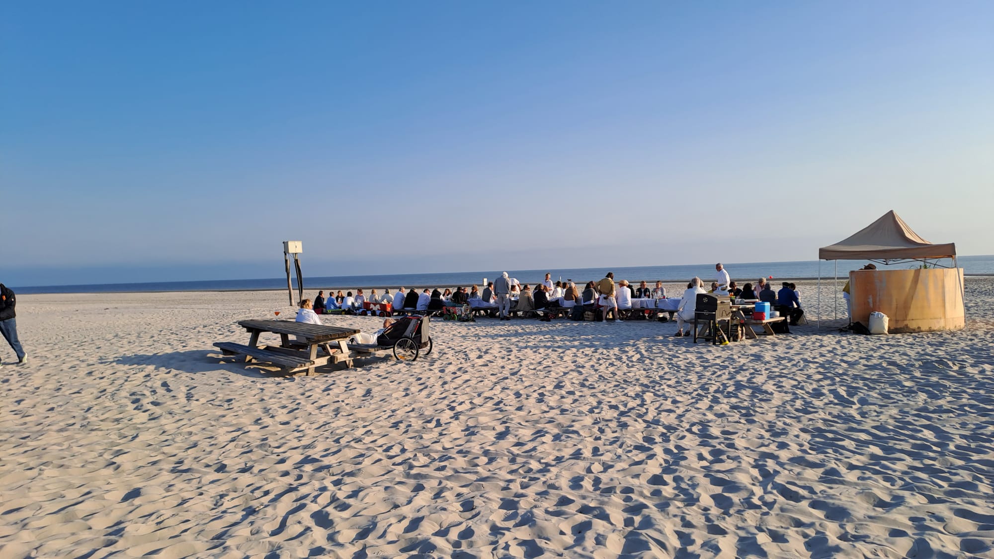 Das White Dinner der Amrumer VHS mit einer langen Tischreihe am Strand, mit 70 Gästen an den Tischen, blauer Himmel oben drüber